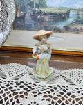 vintage Lefton figurine depicts a Victorian lady in a yellow-striped dress